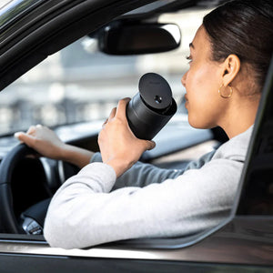 Person trinkt Kaffee aus einem schwarzen Thermobecher mit Schiebedeckel im Auto, Teil von Take away, Fellow, EspressoGear, alles über Kaffee.