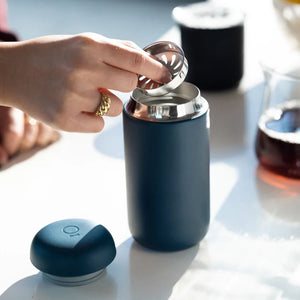 Hand, die einen Filter in eine mattblaue, wiederverwendbare Kaffeetasse einsetzt, Teil von Take away und EspressoGear, alles rund um Kaffee.
