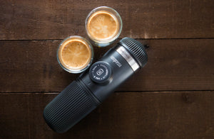 Tragbare Espressomaschine mit zwei Espressotassen auf Holzoberfläche, aus portablen Kaffeemaschinen und Barista-Ausrüstung
