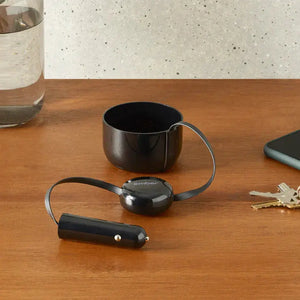 Auto-Ladegerät für Ember elektrische Tasse auf Holztisch mit Autoadapter und Reflexionsdetails.