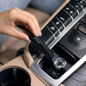Hand, die das Billadegerät für die Ember elektrische Tasse im Zigarettenanzünder des Autos für bequemes Laden anschließt.